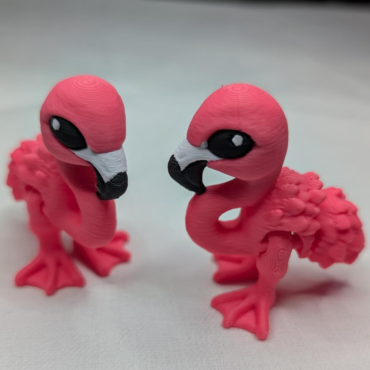 Two pink flamingo figurines on a white background