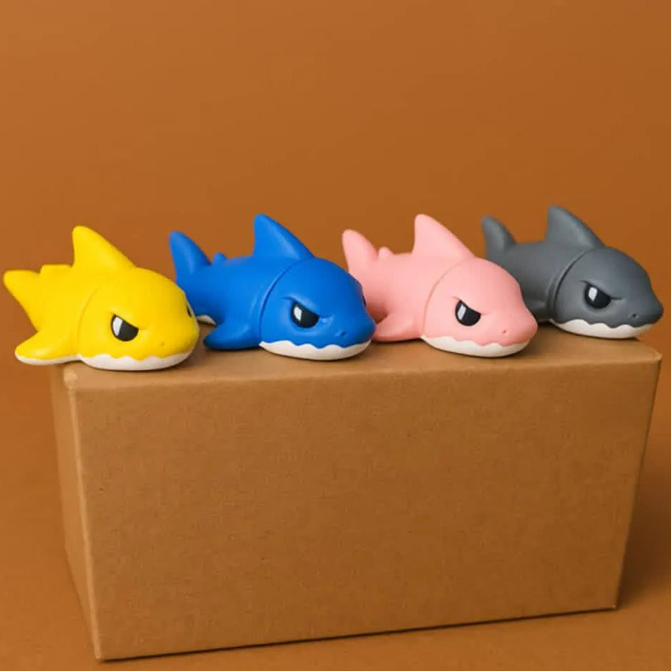 Four colorful shark figurines on a brown box against a brown background
