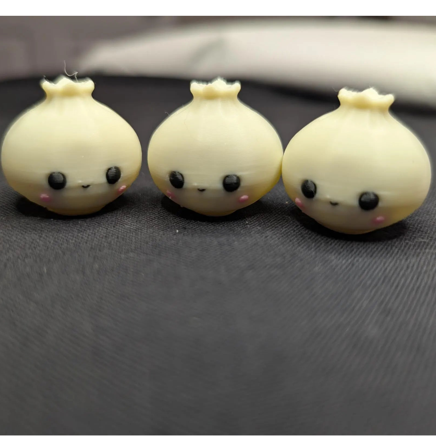 Three cute onion-shaped figurines with faces on a dark surface