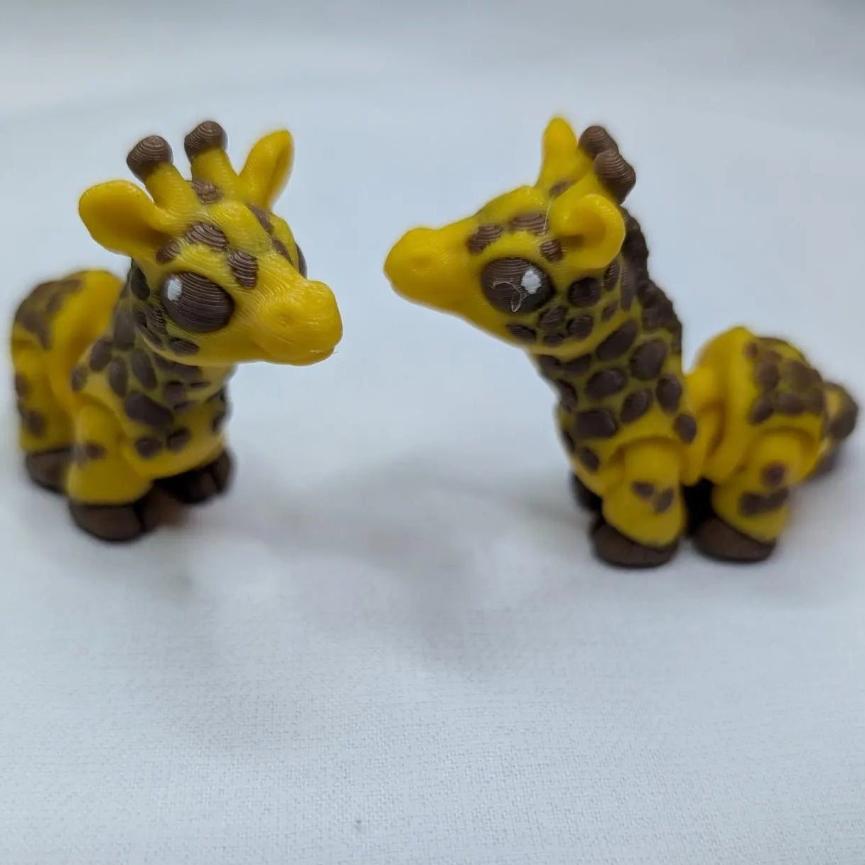 Two small giraffe figurines on a white background