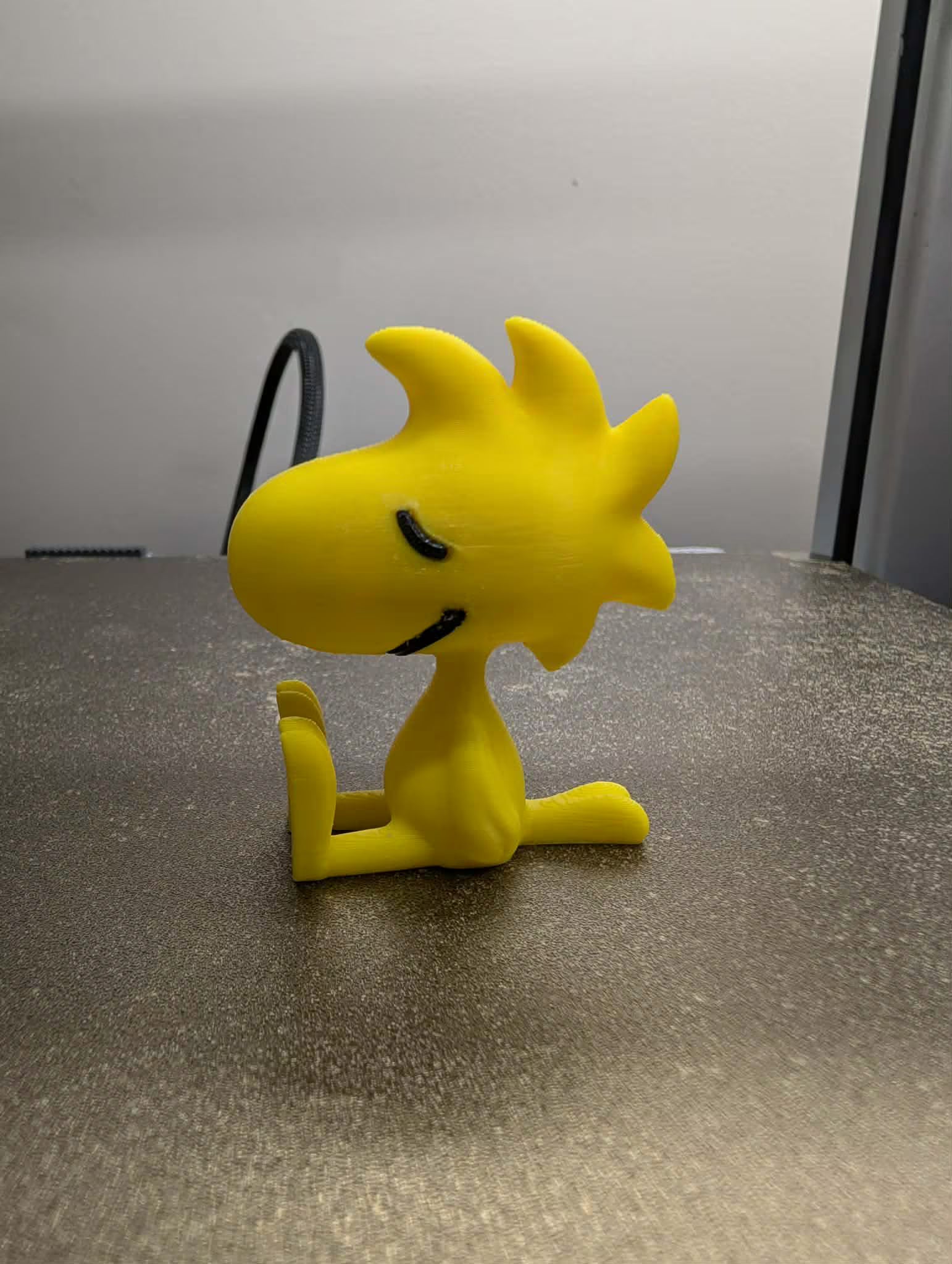 Yellow cartoon character figurine on a gray surface