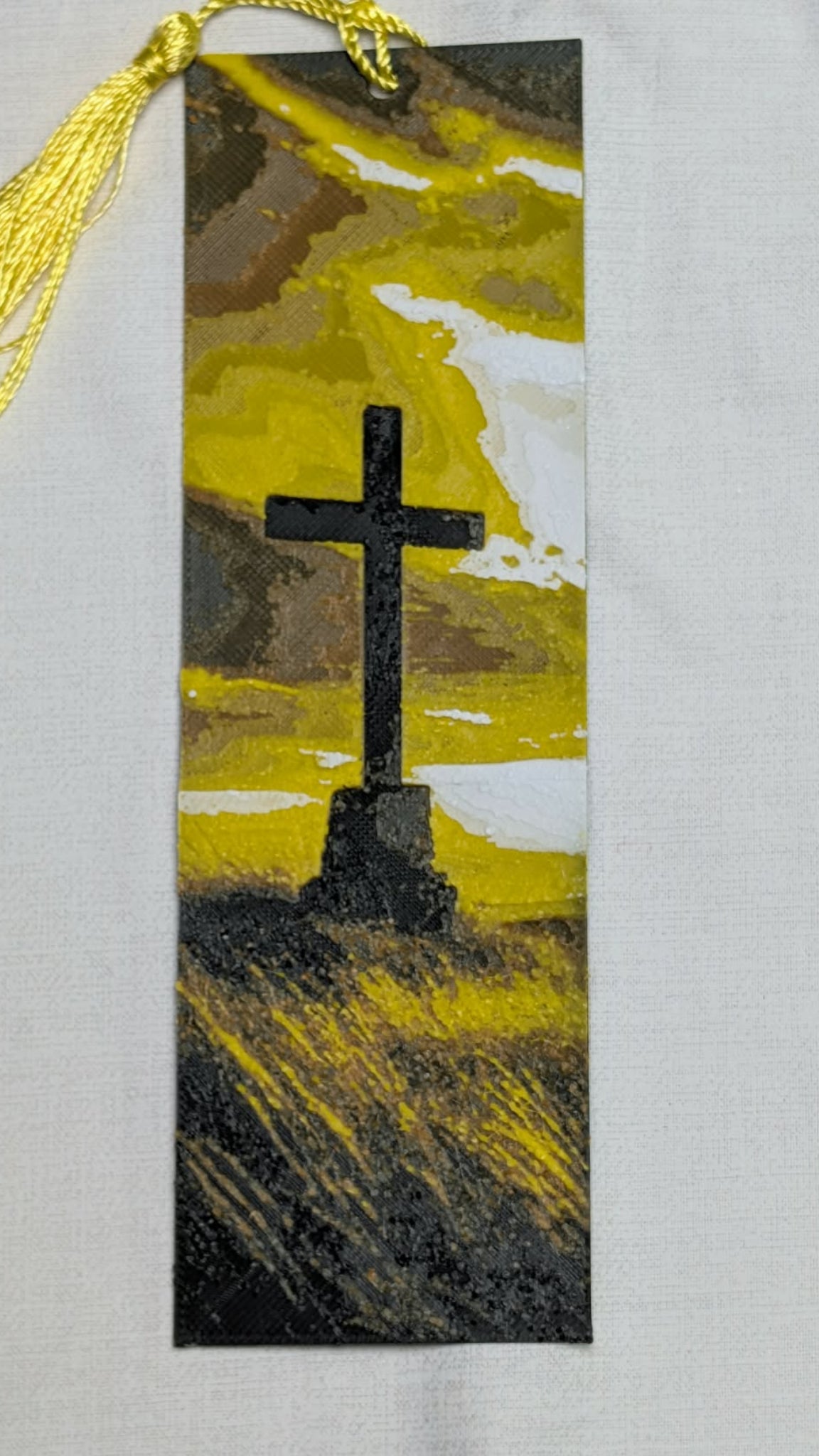 Artistic depiction of a cross on a textured surface with a yellow tassel.