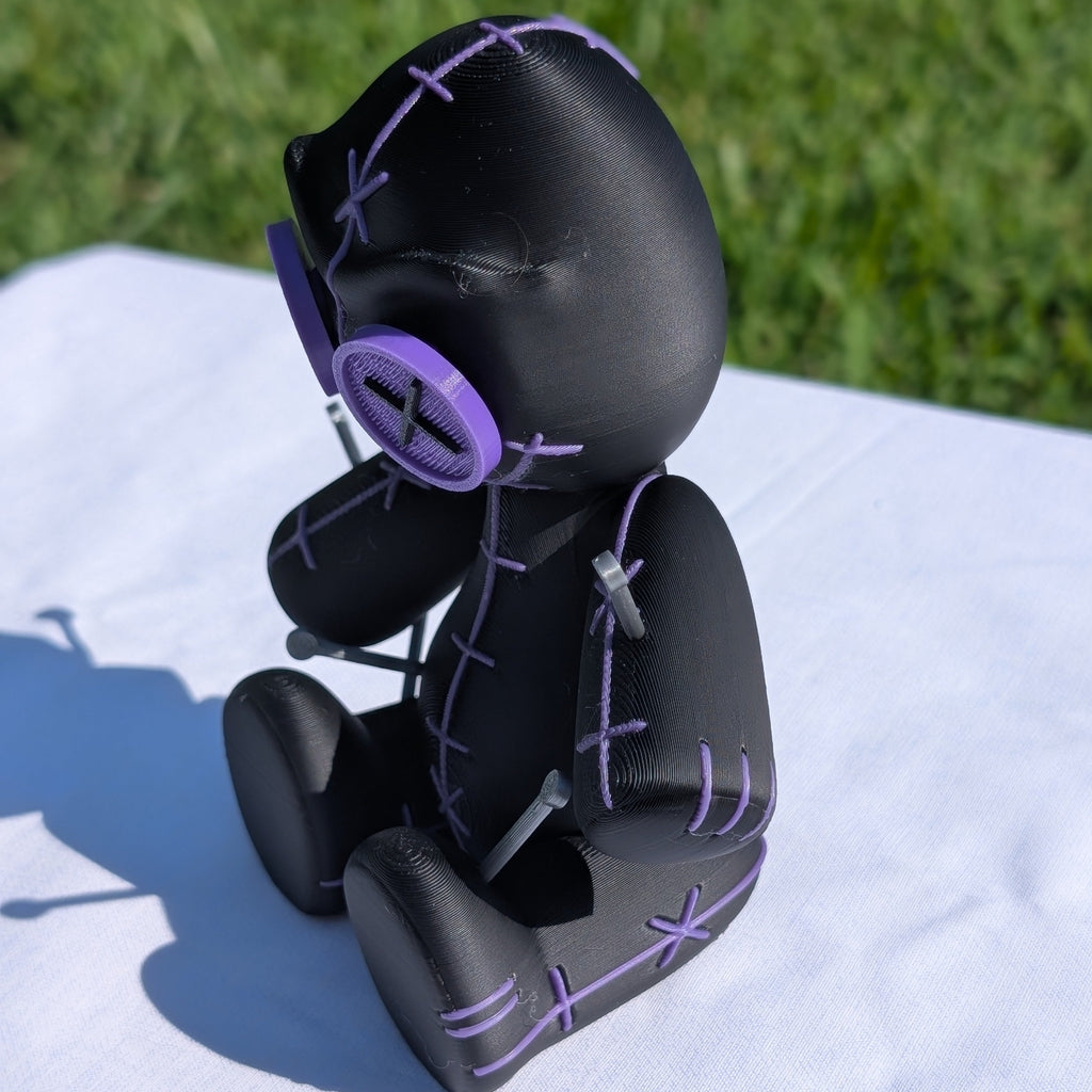 Black and purple toy figure on a white surface with grass in the background