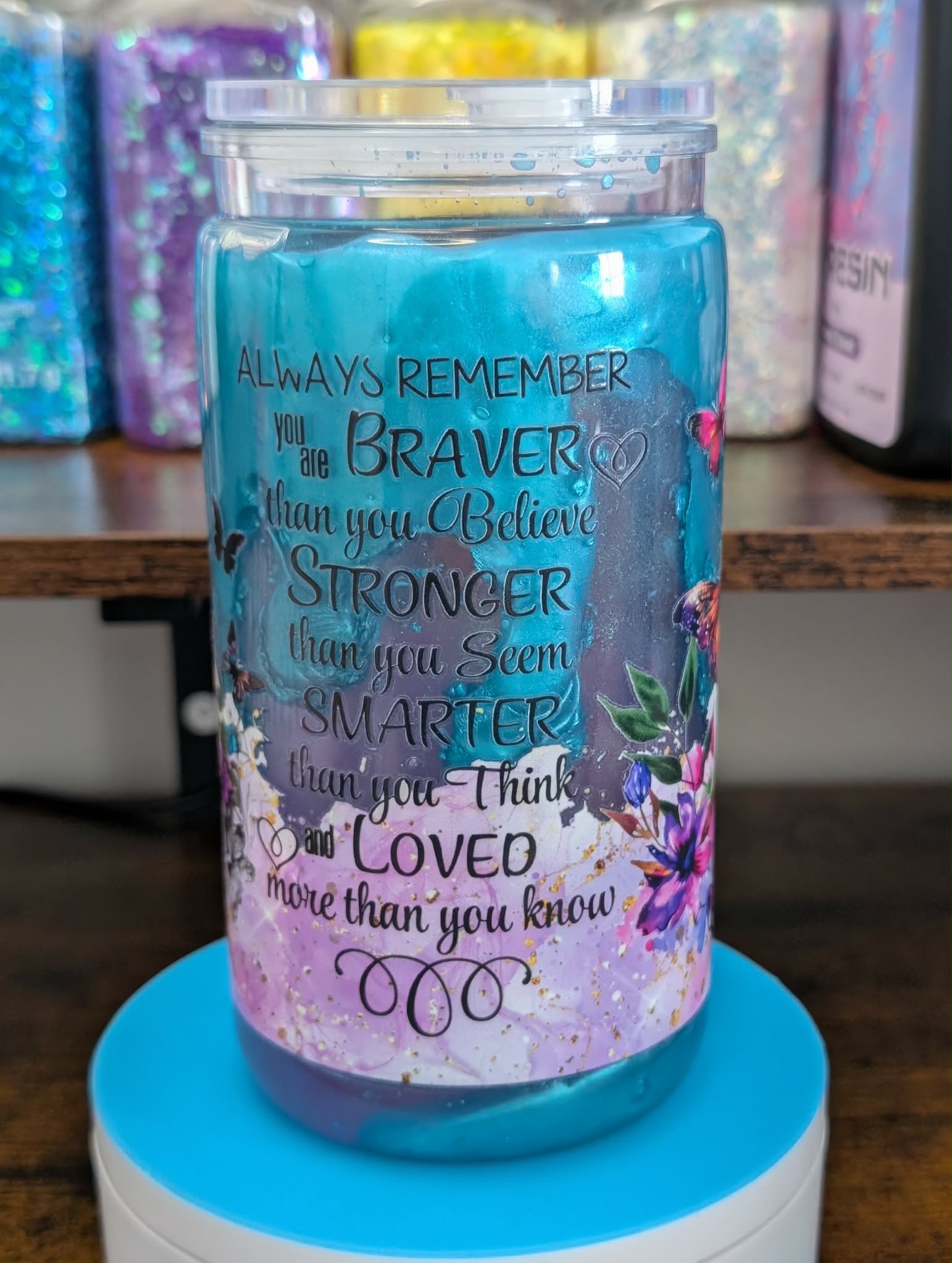 Tumbler with motivational quote and floral design on a blue stand