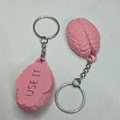 Pink brain-shaped keychains with 'USE IT' text on a light gray background