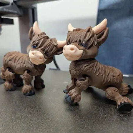 Two brown figurines resembling boars on a reflective surface with a blurred background.