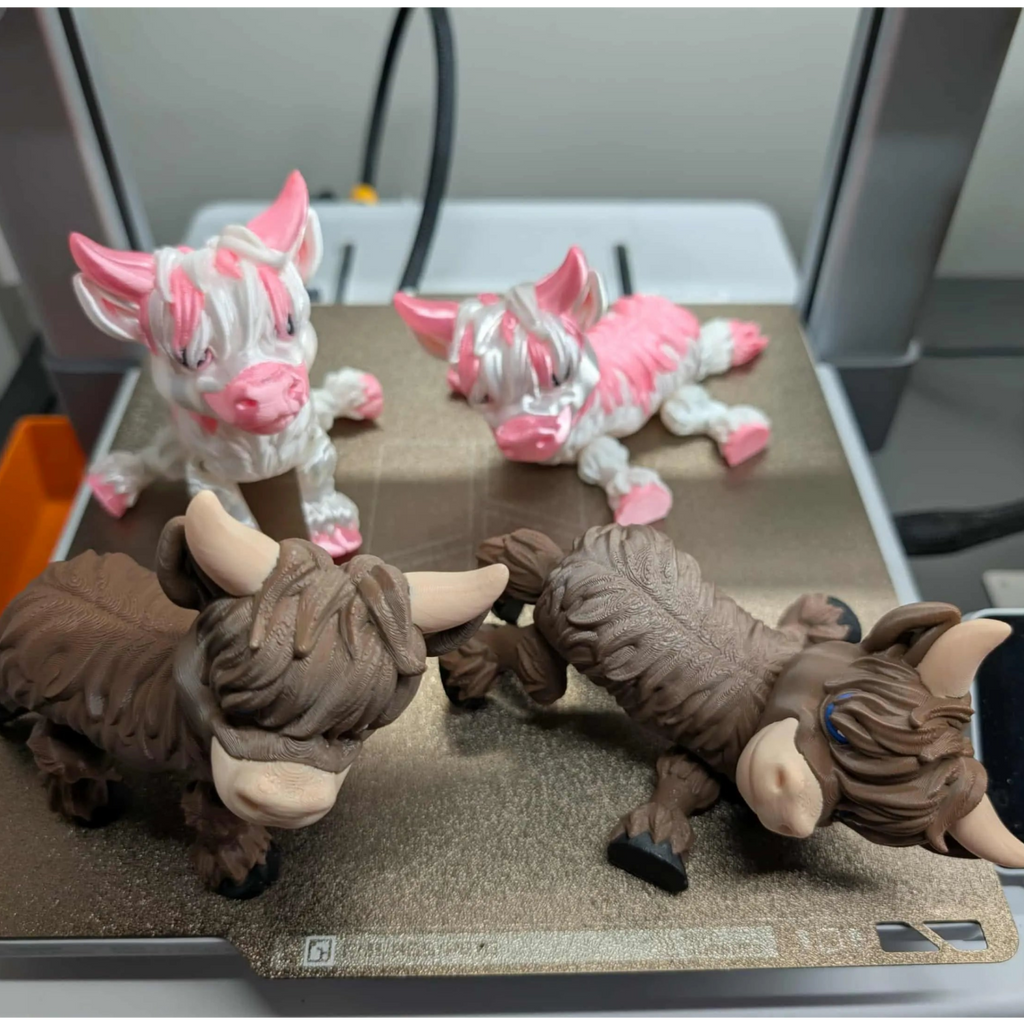 Two brown bull-like figurines and two pink cow-like figurines on a glass surface.
