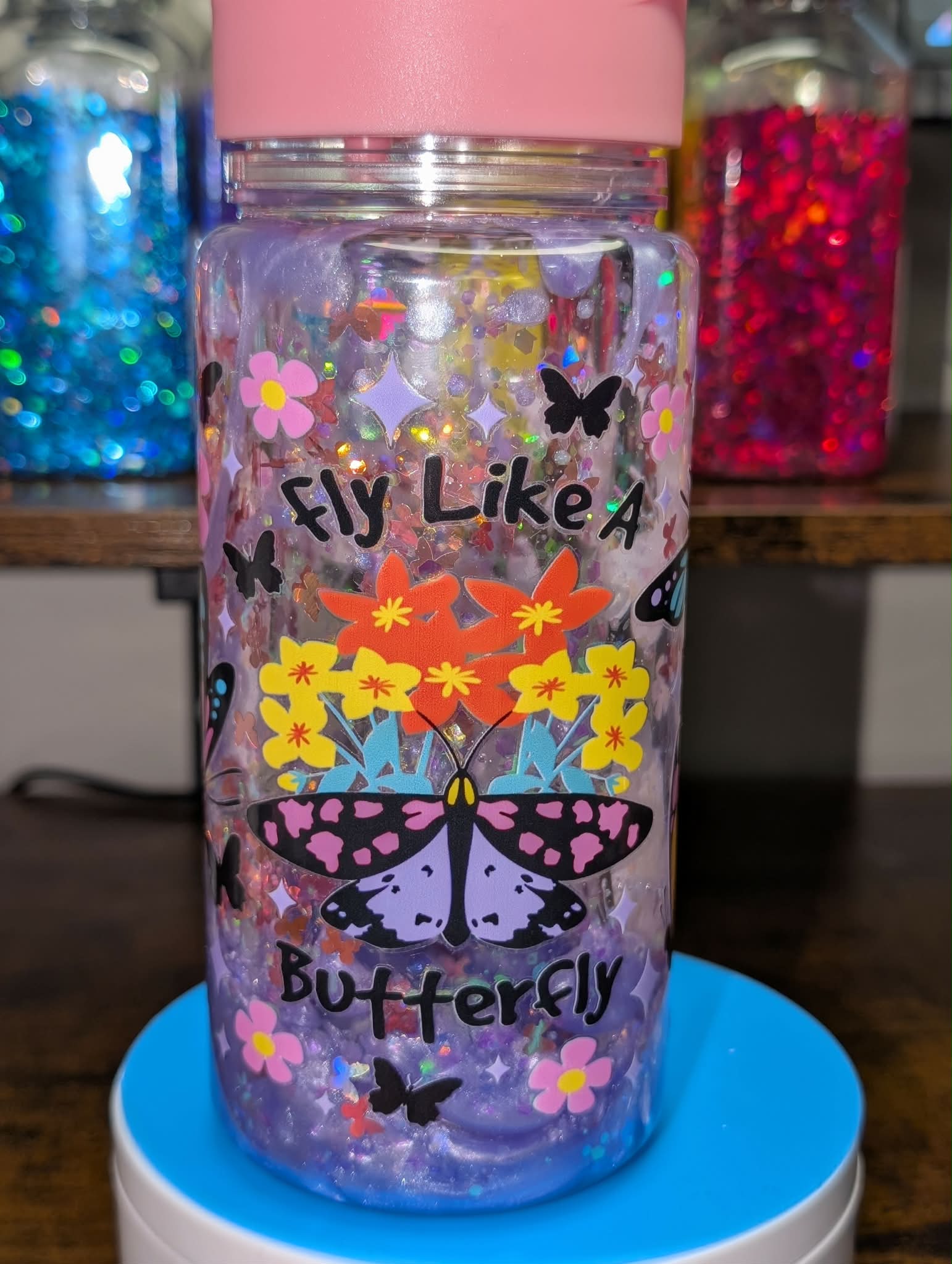 Colorful water bottle with butterfly design and text on a blue stand.