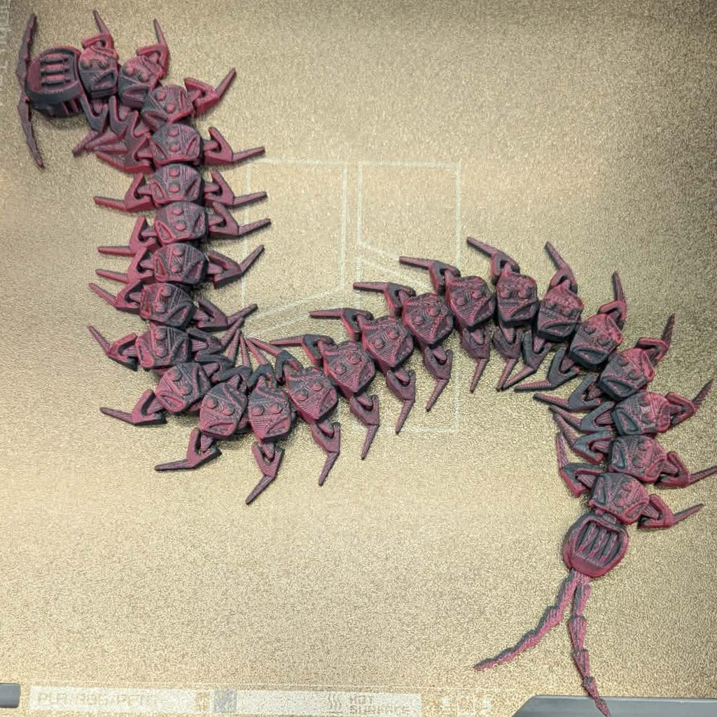 Red and black insect-like creature model on a beige background