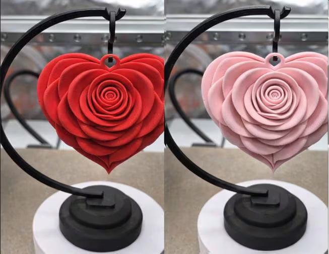 Two heart-shaped rose decorations, one red and one pink, on black stands.