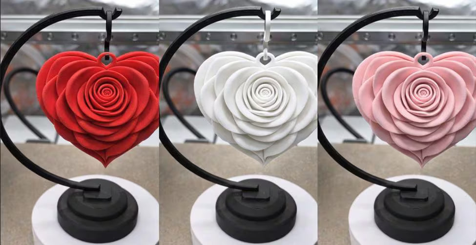 Three heart-shaped rose decorations in red, white, and pink on a stand.
