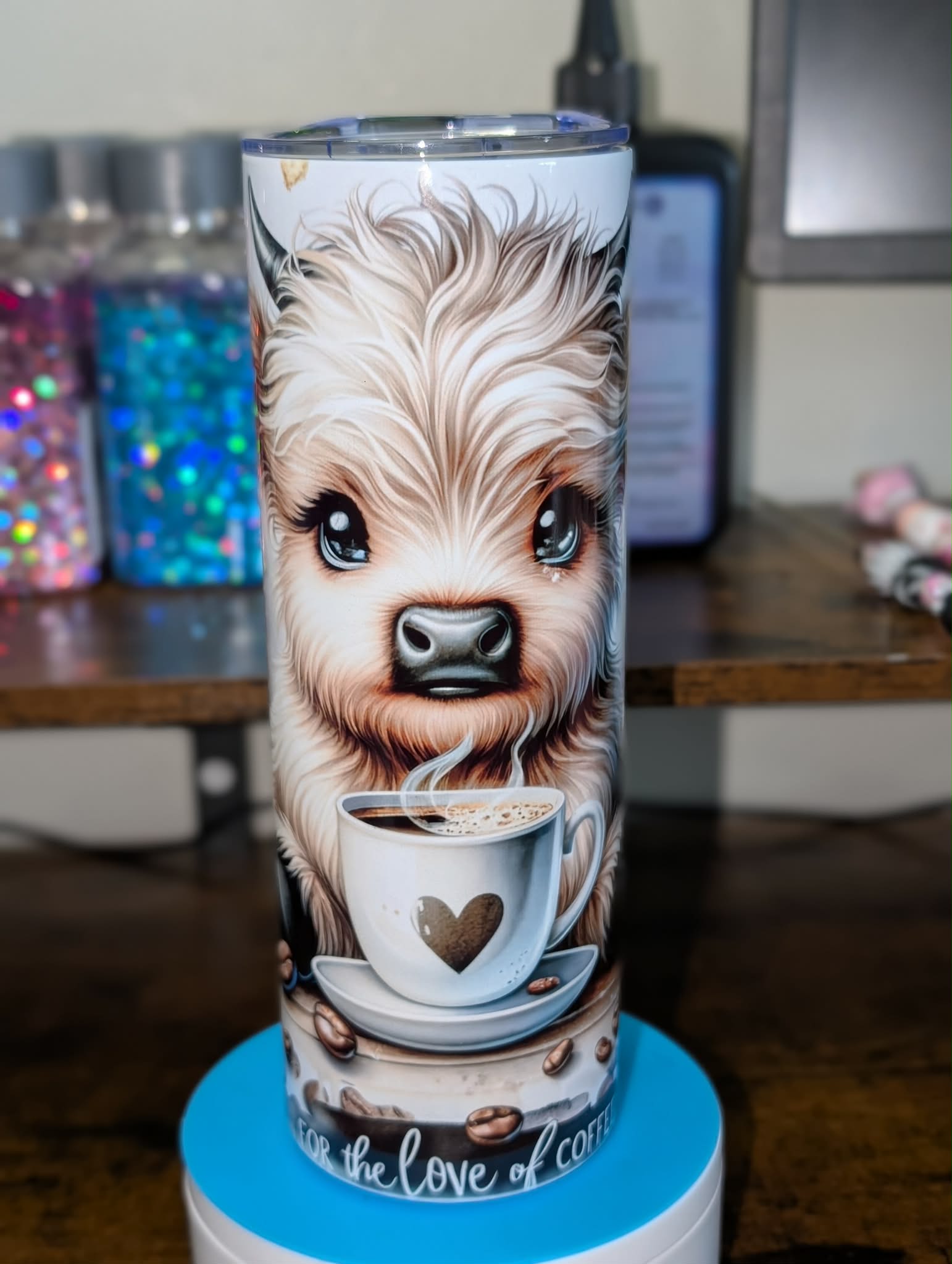 Tumbler with a cow design holding a coffee cup on a wooden surface.