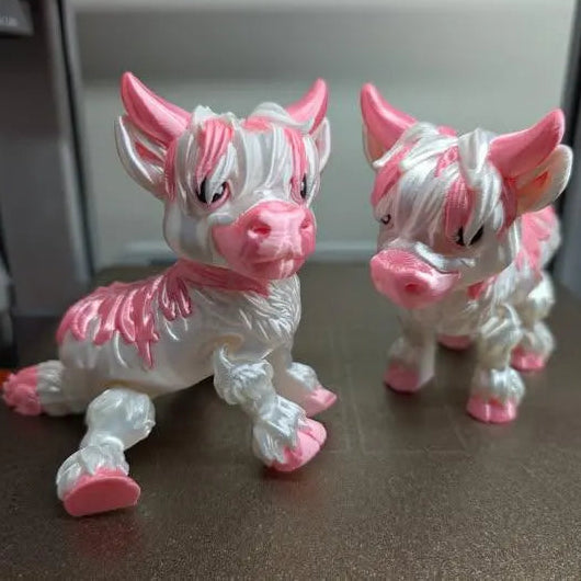 Two pink and white animal figurines on a surface with a blurred background