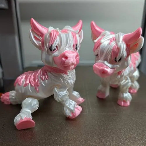 Two pink and white animal figurines on a surface with a blurred background