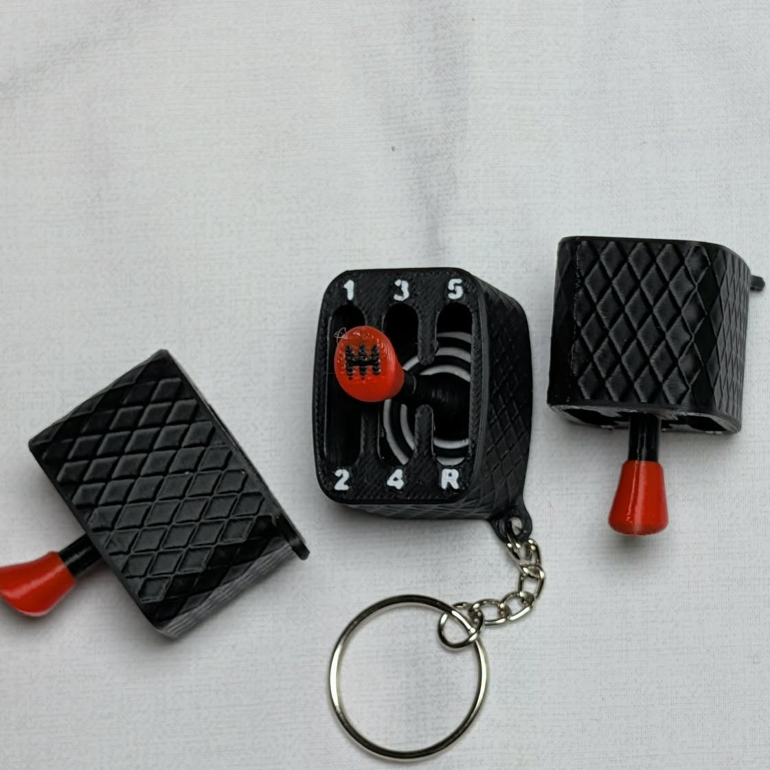 Black and red keychain with a dial and textured ends on a light gray background