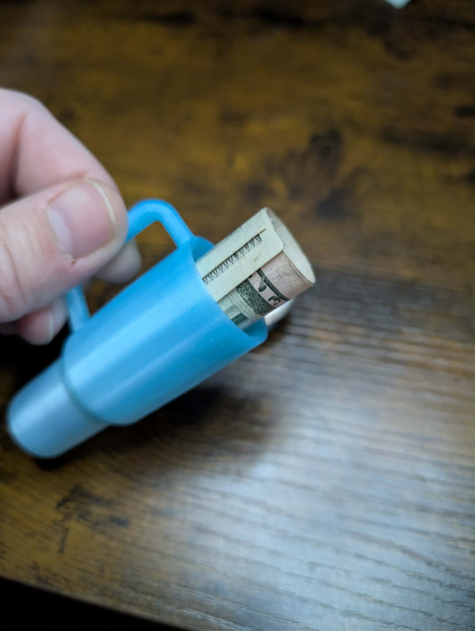 Mini tumbler keychain holding folded cash inside for storage