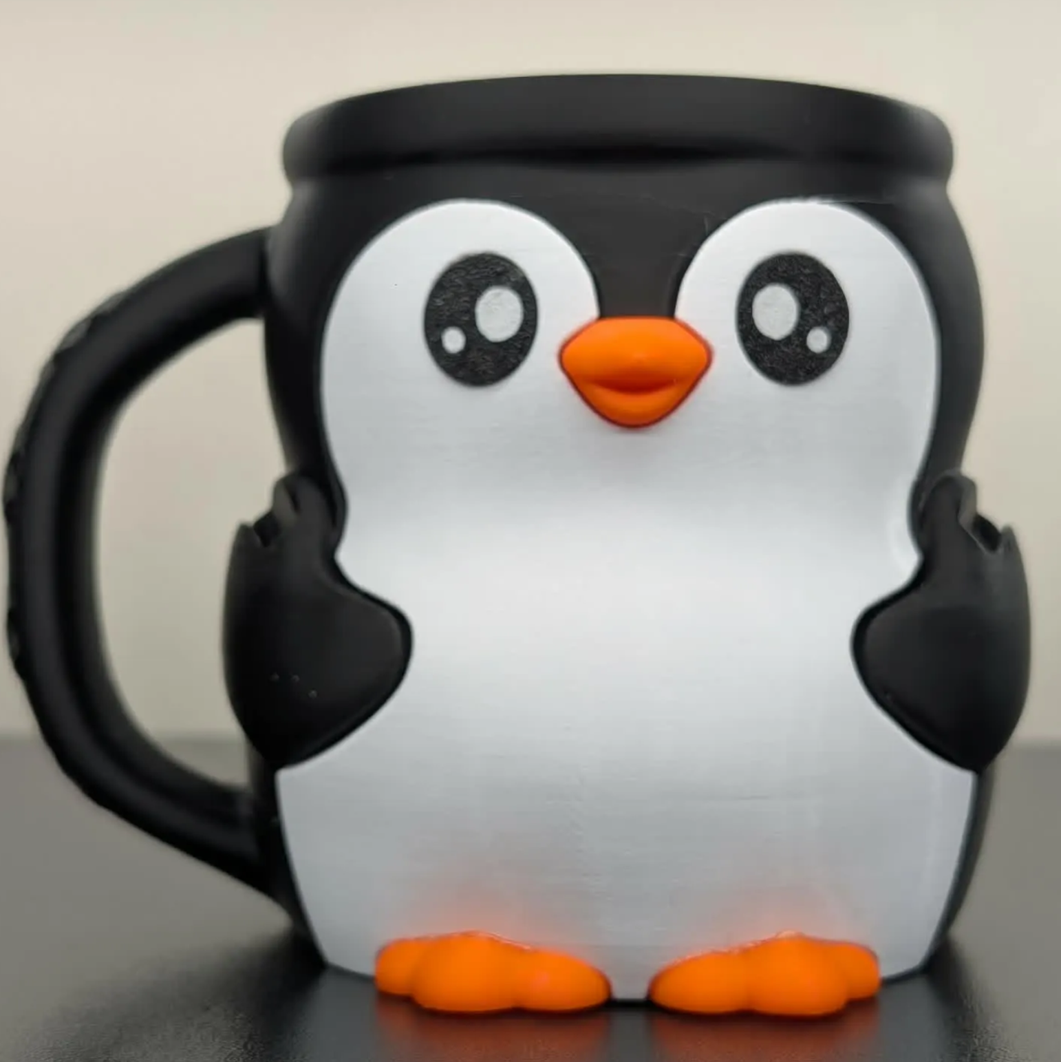 Penguin-shaped mug with black, white, and orange colors on a neutral background