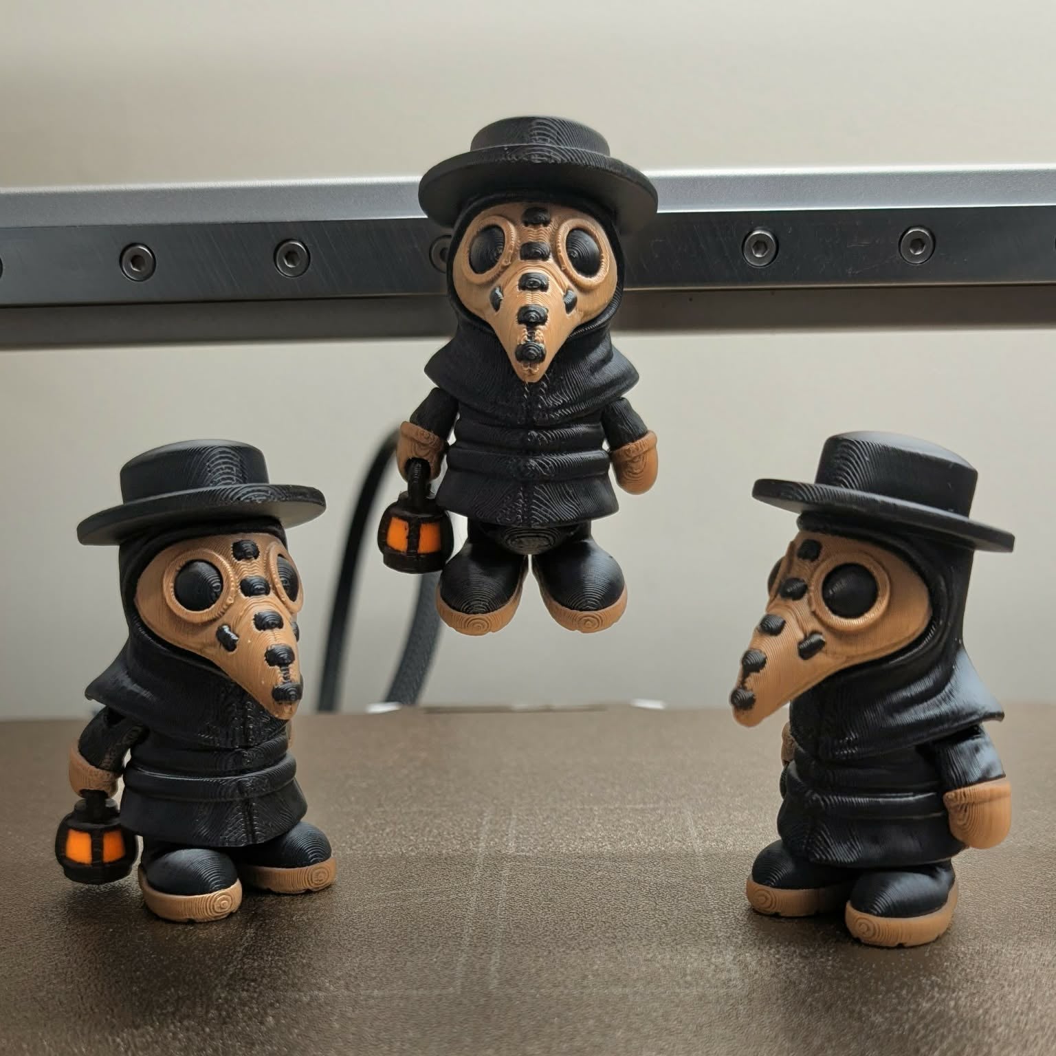Three small figurines with plague doctor masks and top hats on a reflective surface.