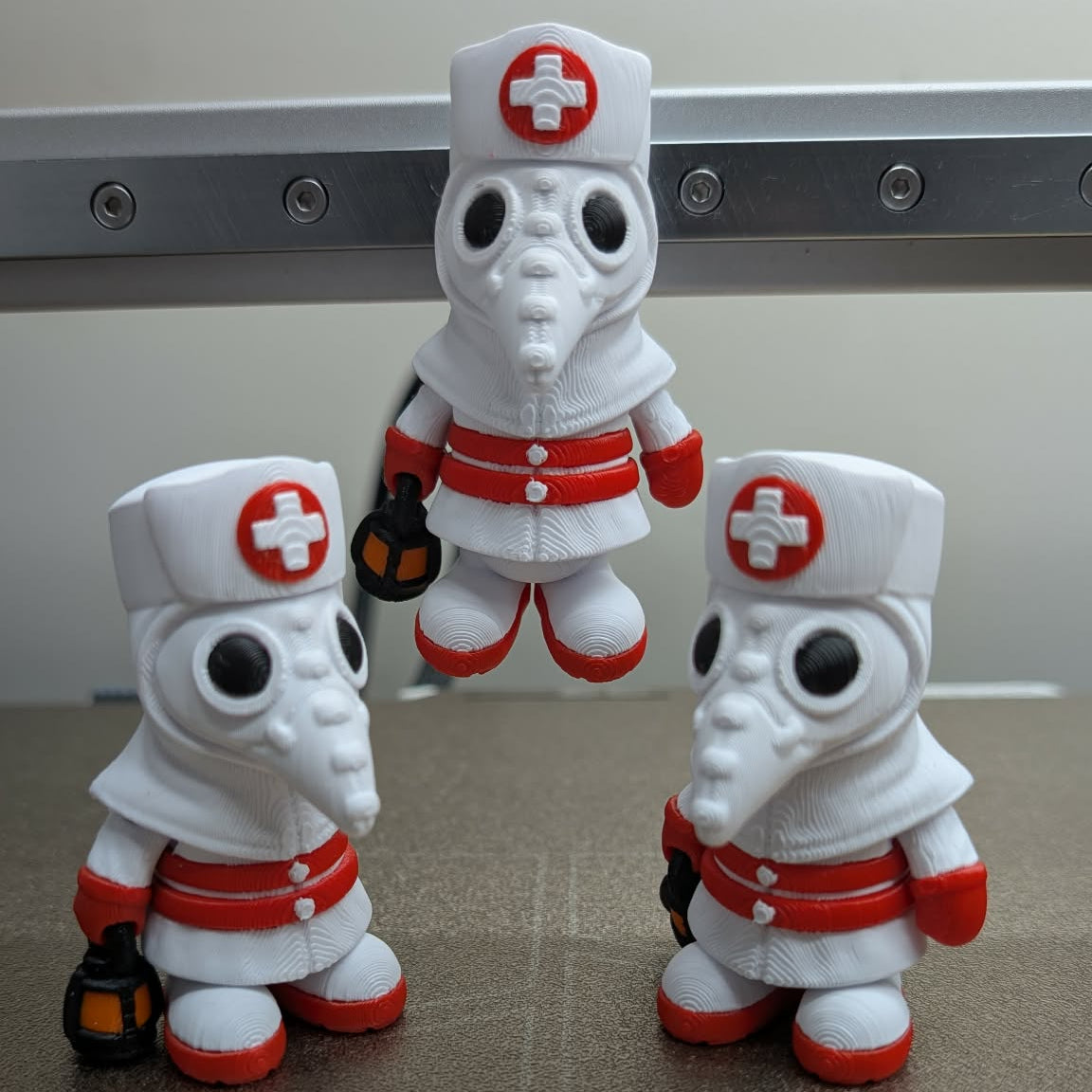 Three toy figures of a character in a nurse outfit with a red cross on a neutral background