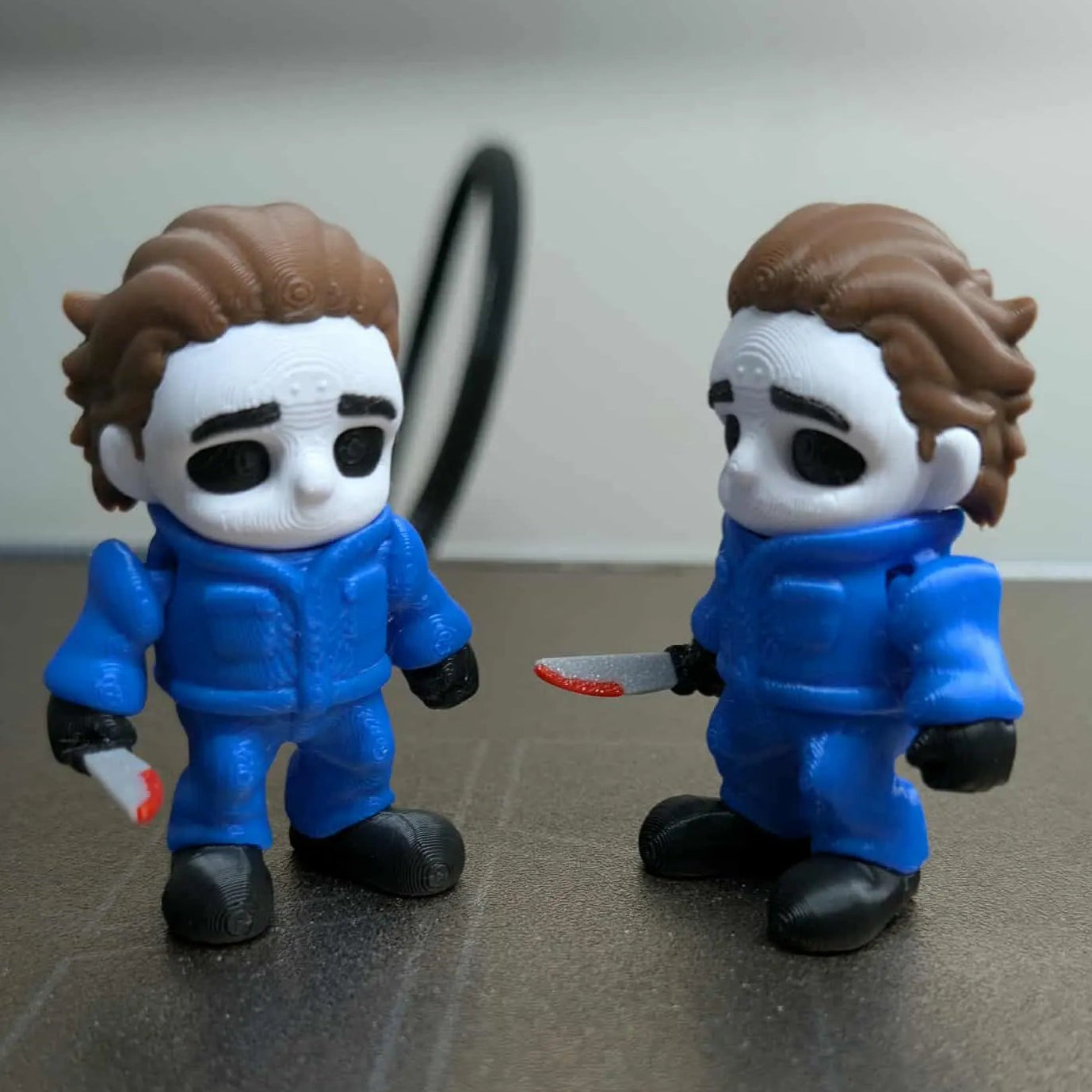 Two toy figures in blue jumpsuits on a reflective surface with a white background