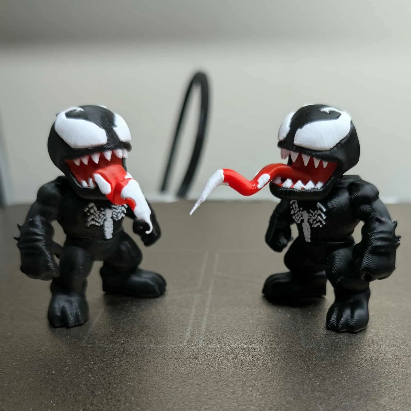 Two black and white figures with red accents on a metallic surface.