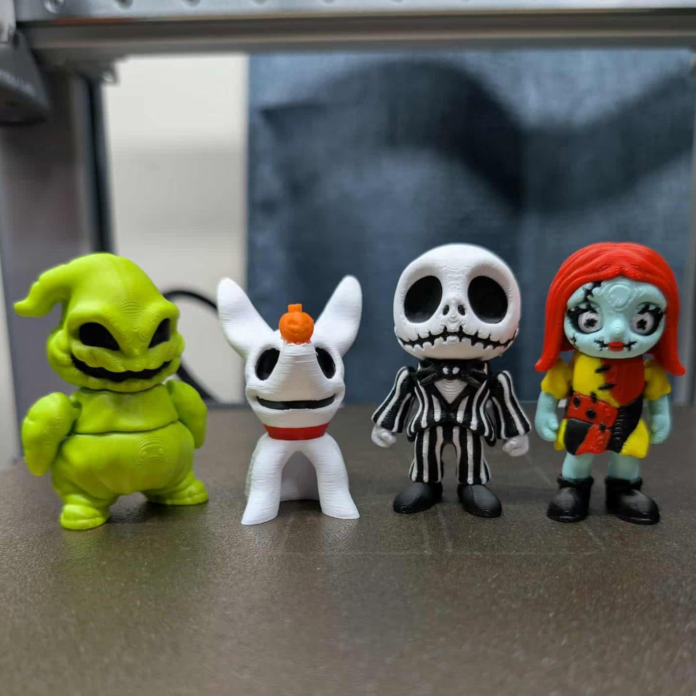 Four colorful figurines on a metallic surface with a blurred background