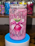 Pink glittery tumbler with decorative elements on a wooden surface
